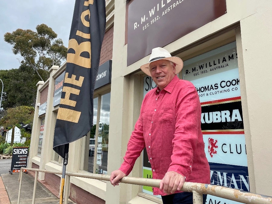 Ross standing in front of The Bloke Shop and smiling. Behind him are menswear brands on display in the window such as Akubra, Thomas Cook, FXD and more.